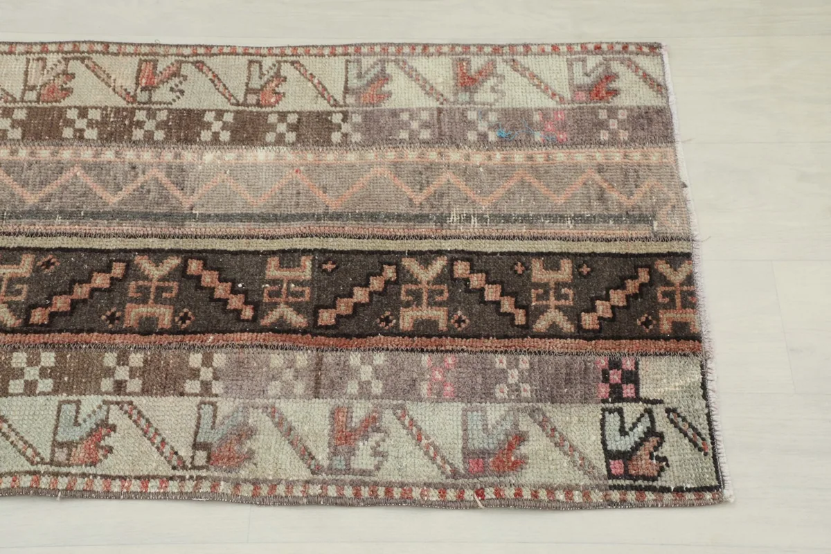 Close-up detail of the vintage runner's patterns, showing beige, brown, and rose tribal motifs.