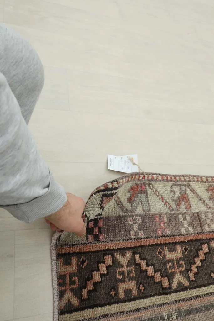 Hand gently pressing into the low wool pile of the vintage Anatolian runner, showing its texture.