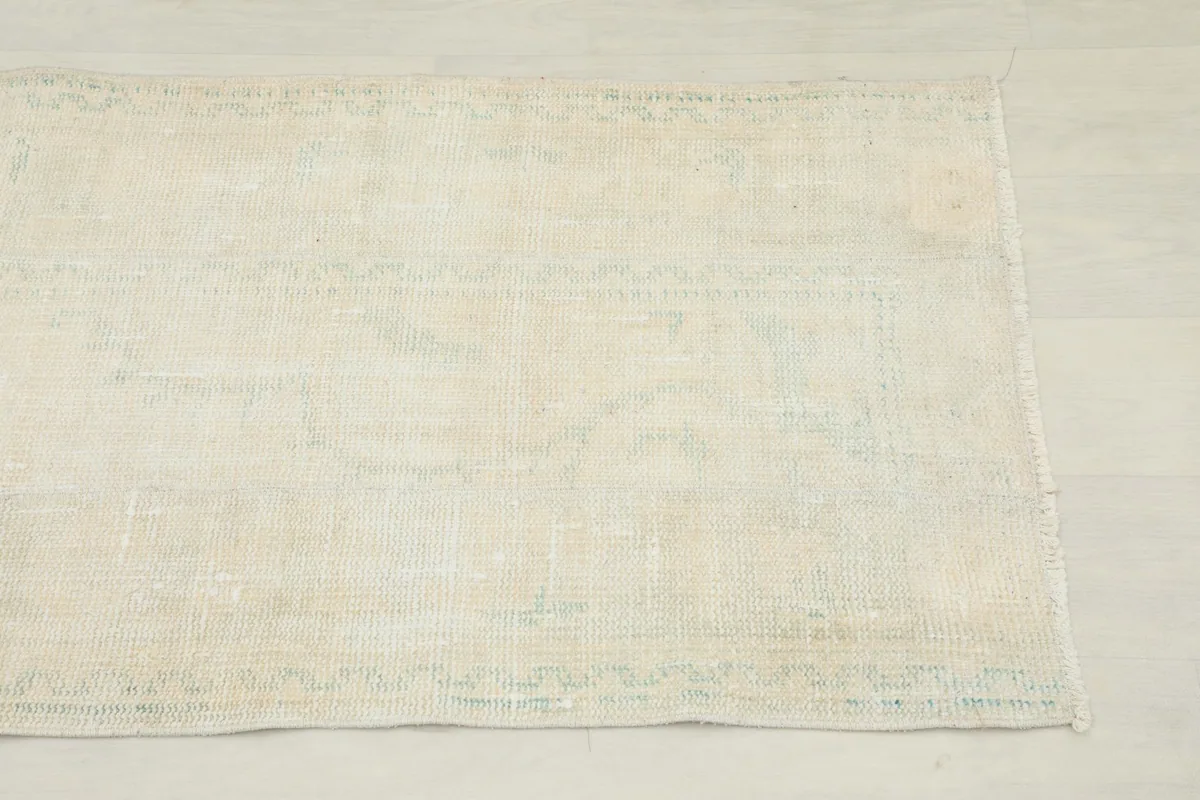 Close-up of the runner rug's surface, showing subtle geometric patterns in ivory and beige tones.