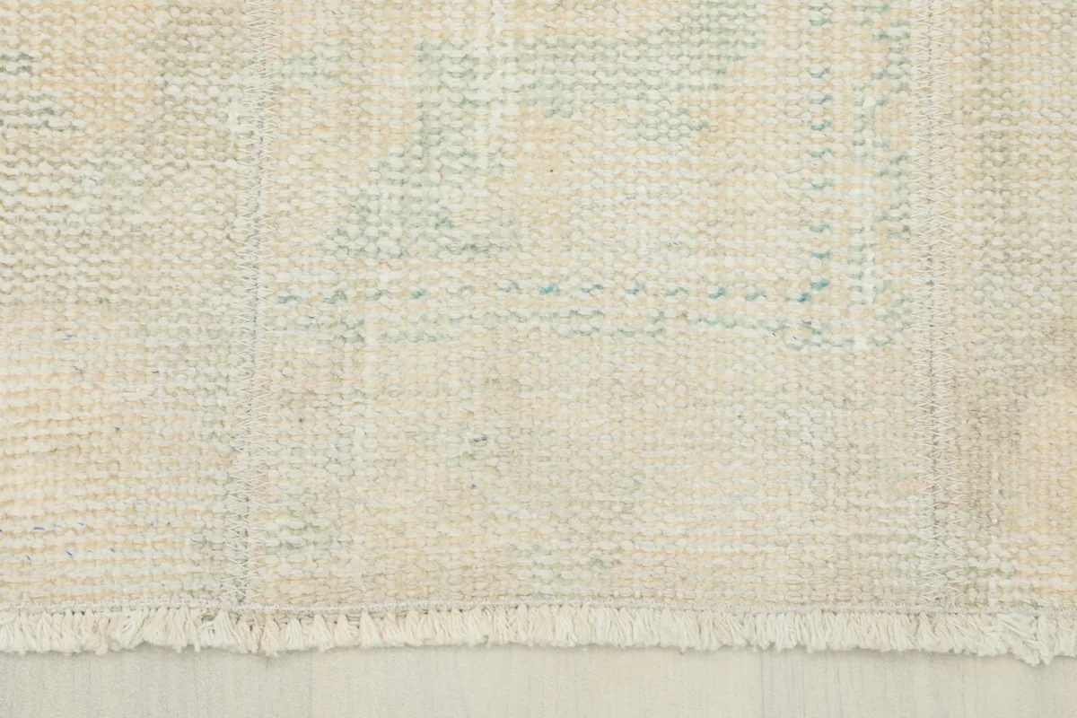 Detail of the rug's short, natural fringe and the hand-knotted structure near the edge.