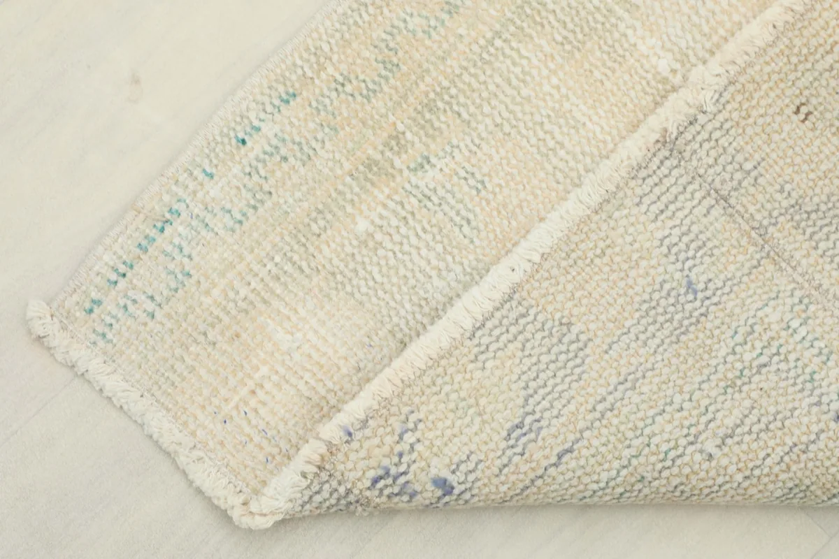 Corner of the rug folded over, displaying both the front and back of the hand-knotted textile.