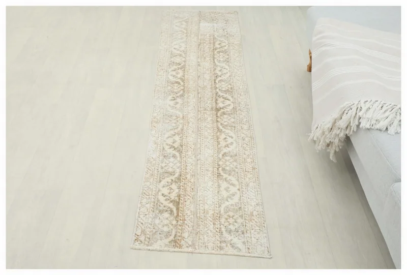 Full top view of a distressed beige and tan vintage runner rug on a light floor