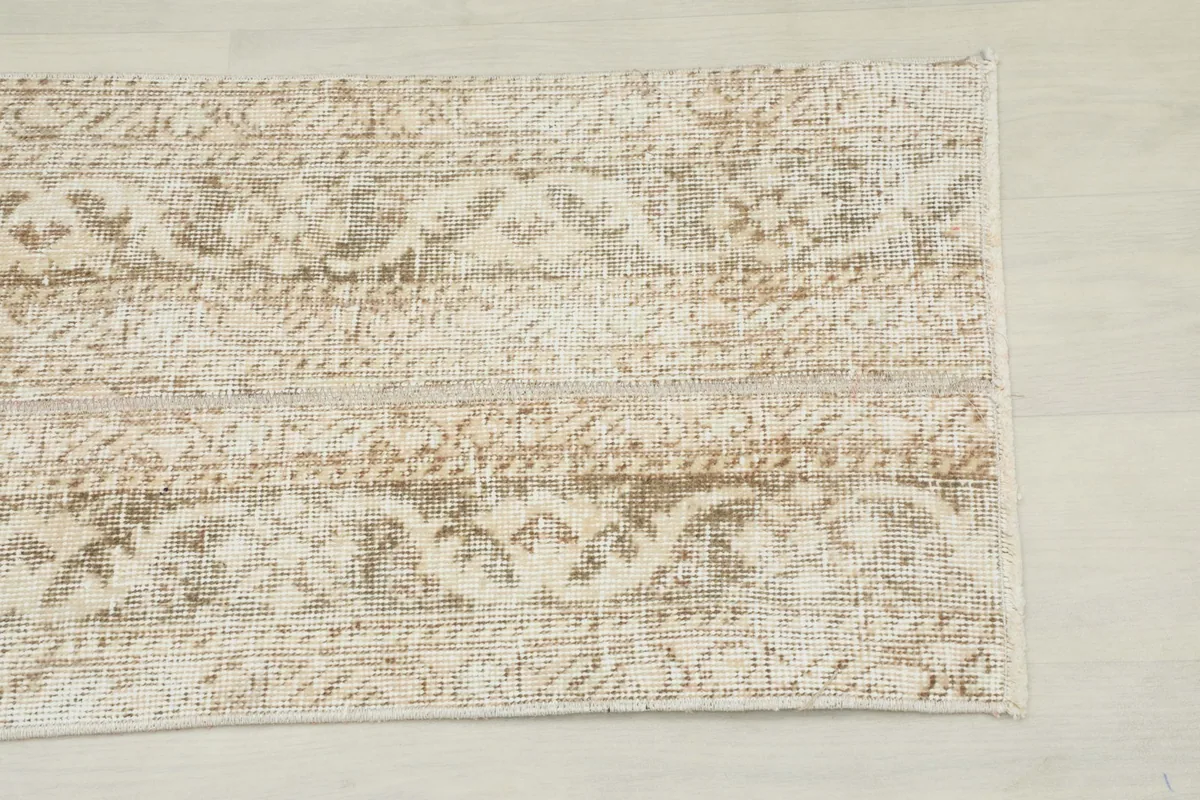 Close-up of the distressed abstract pattern in beige, tan, and gray on the rug