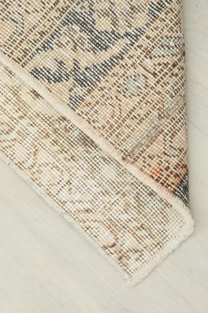 Corner of the rug folded to reveal the cotton foundation and reverse side