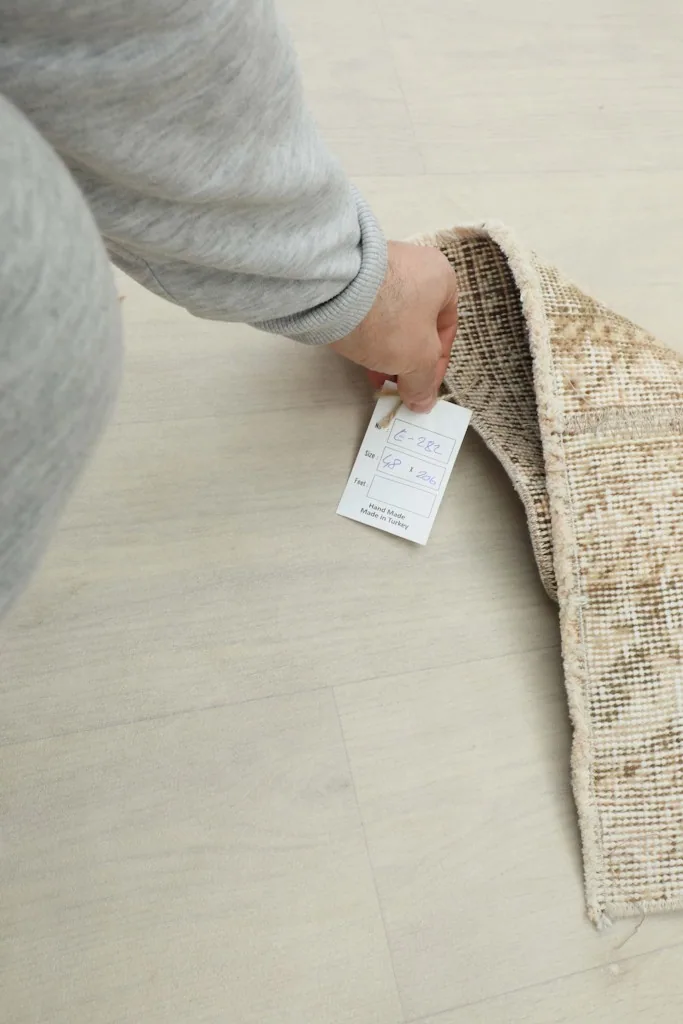 Hand holding a product tag on the vintage wool runner, indicating quality and origin