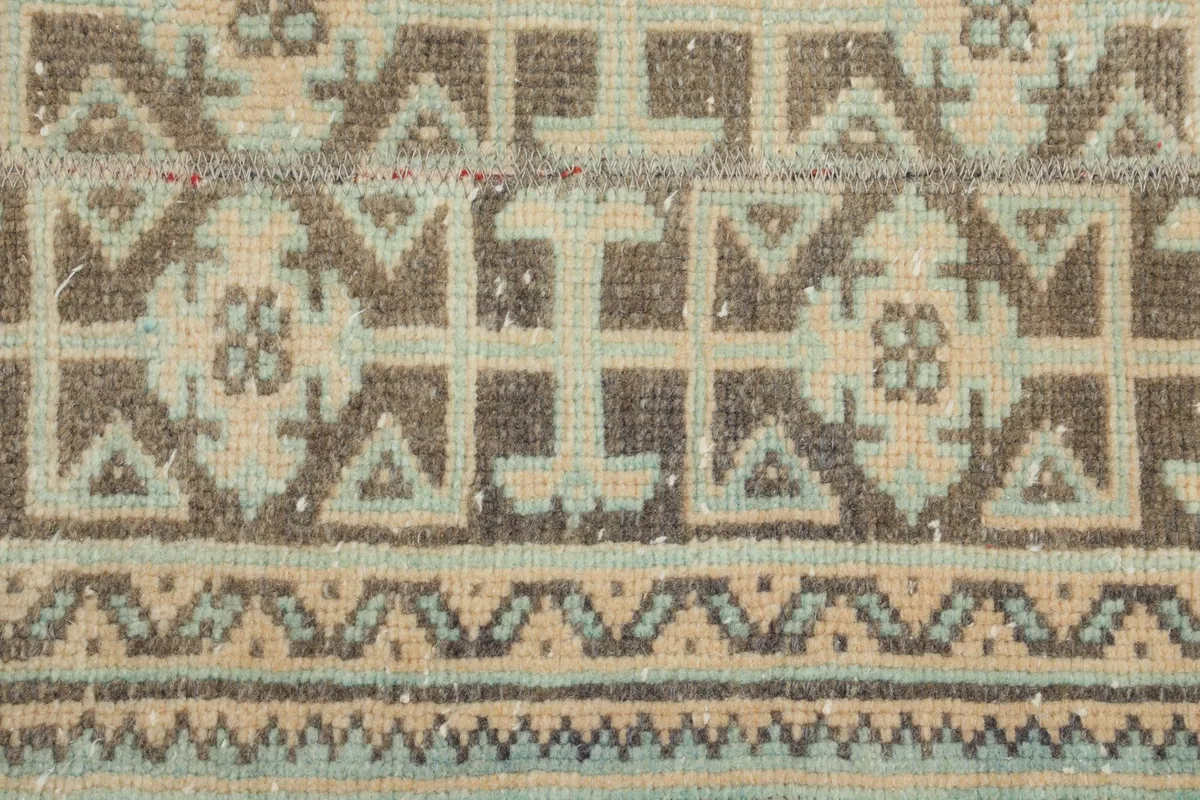 Texture and color variations in the beige, brown, and blue geometric motifs of the rug