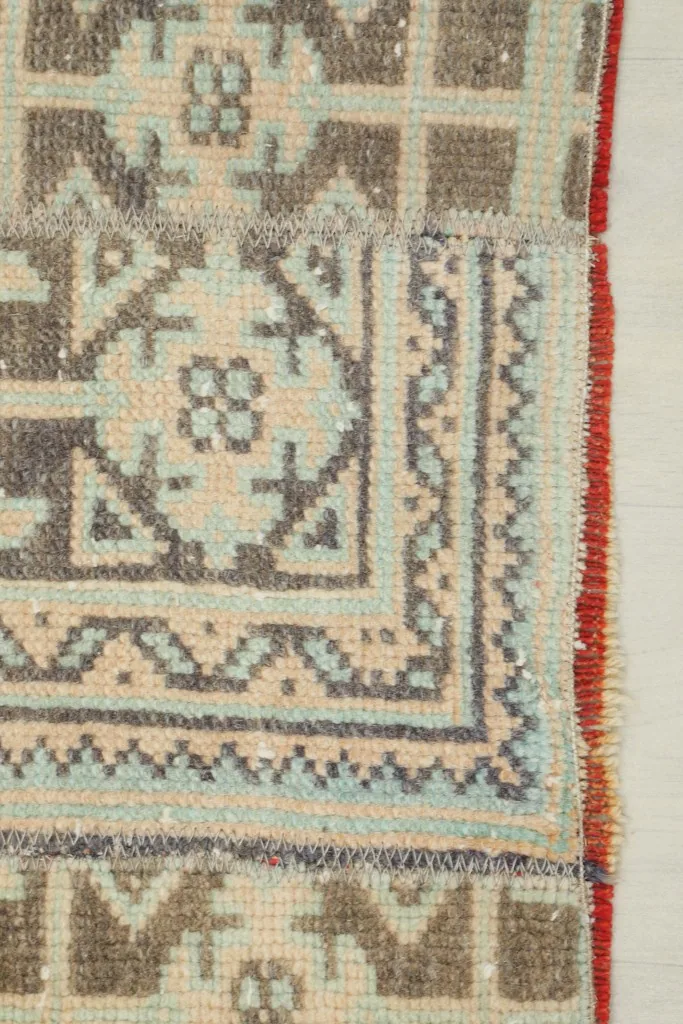 Corner detail showing the hand-knotted edge and the rust-colored side finish of the rug