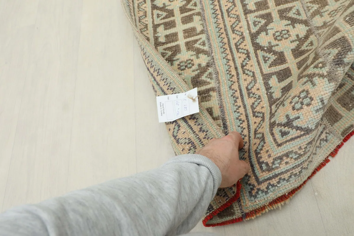 Hand holding the rug to show the cotton foundation and the reverse side of the hand-knotted construction