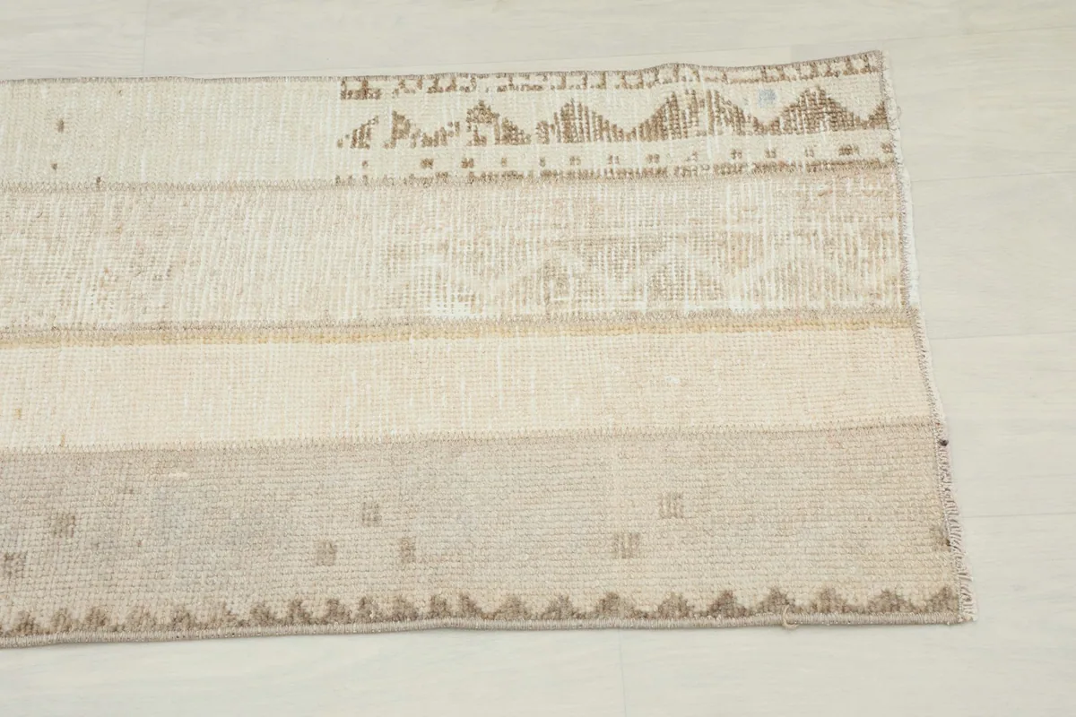 Close-up detail of the tan geometric and tribal motifs along one end of the runner rug.