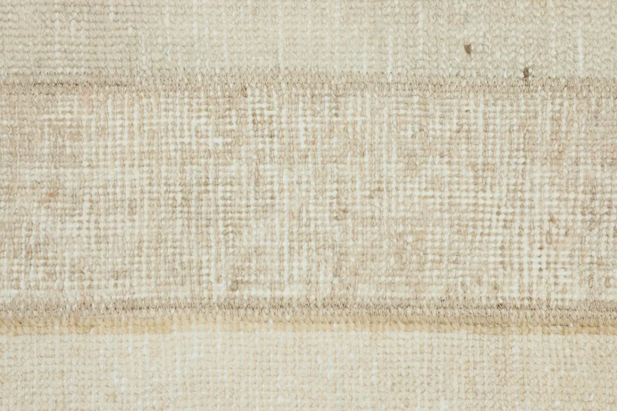 Detailed view of the intricate weave and slight wear on a beige patterned section of the rug.