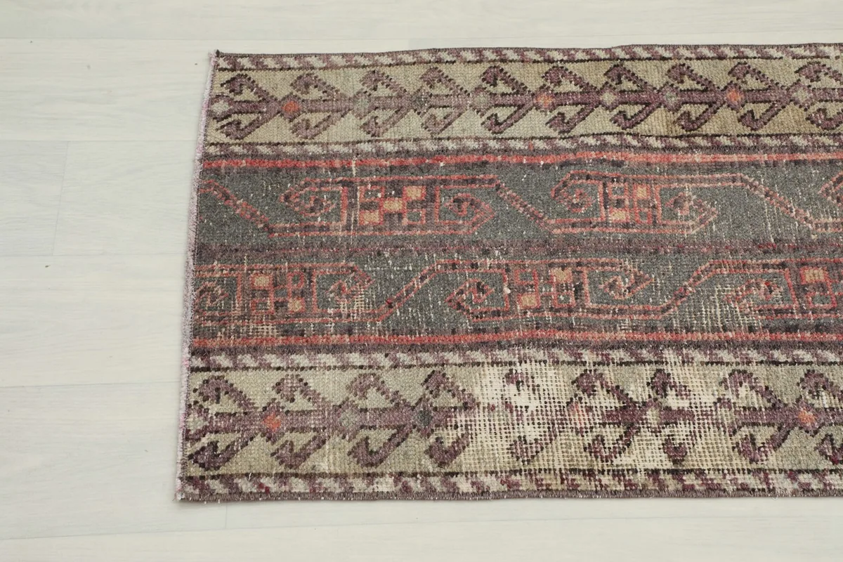 Detail showing the geometric patterns in rust and red within the charcoal central field