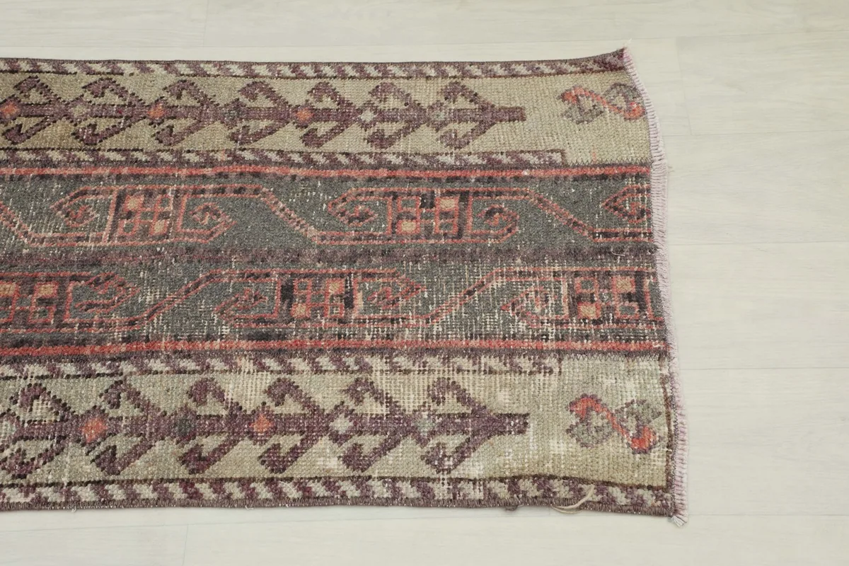 Close-up of the beige border with purple-brown stylized motifs and the charcoal field
