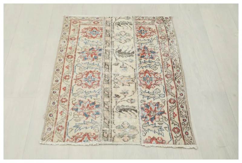 Full overhead view of the beige, red, and blue floral vintage Anatolian area rug.
