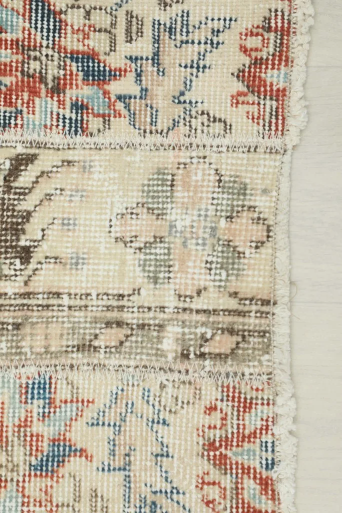 Close-up of the rug's edge, highlighting the vintage wear and individual knot details.