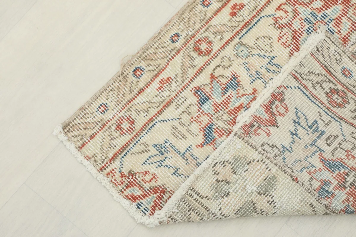 Corner of the rug folded back, revealing the cotton foundation and the reverse side.