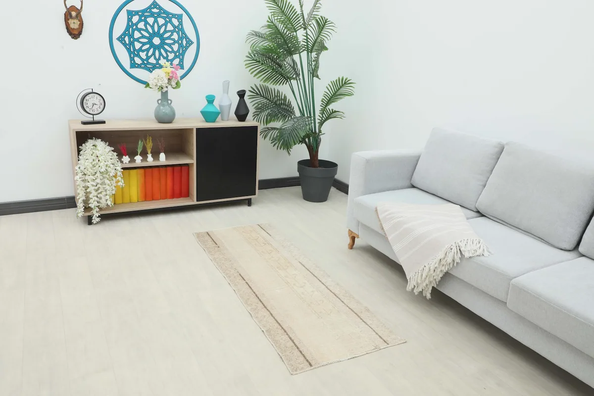 Vintage cream runner rug placed in a modern living room setting, showing its scale next to a sofa.