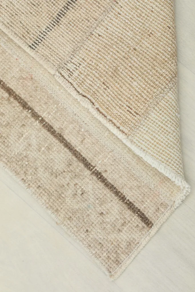 View of the underside and edge of the vintage runner rug, showing its cotton foundation and hand-knotted structure.
