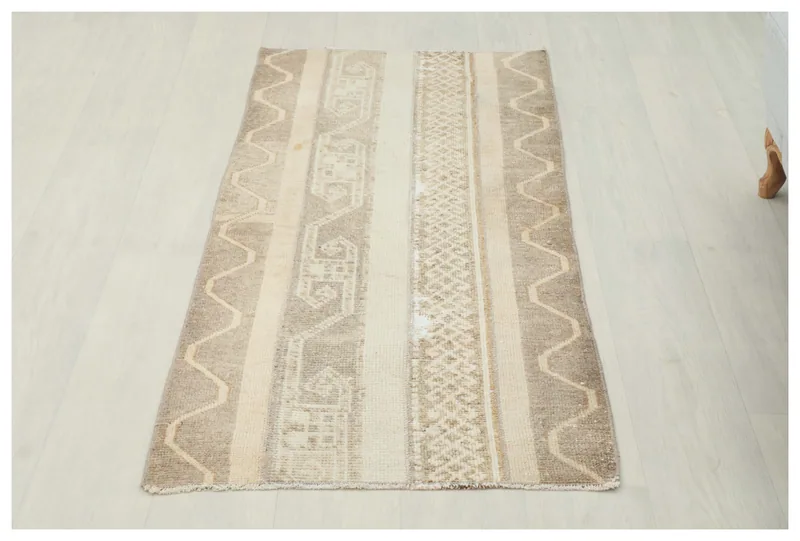 Full top view of the beige and tan vintage Anatolian area rug on a white floor.