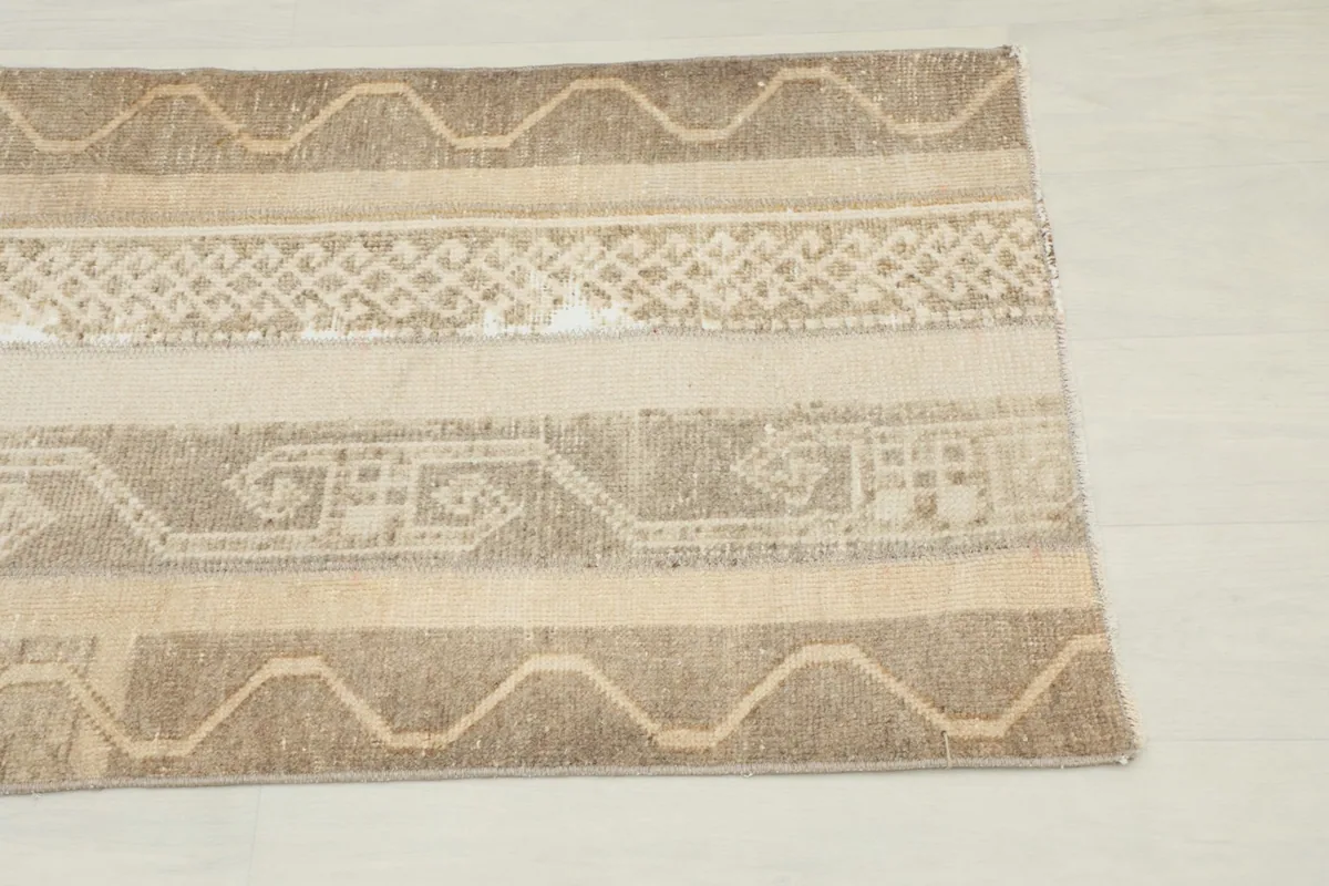Close-up of the rug's border and central geometric motifs in beige and tan.