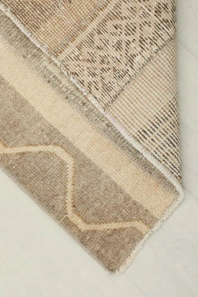 Corner of the rug folded back to reveal the hand-knotted construction on the cotton foundation.