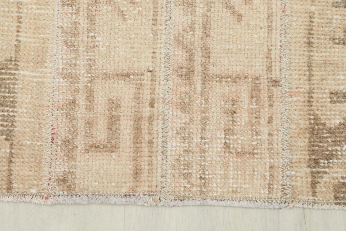 Close-up of the rug's edge, showing the subtle wear and character of the vintage piece.