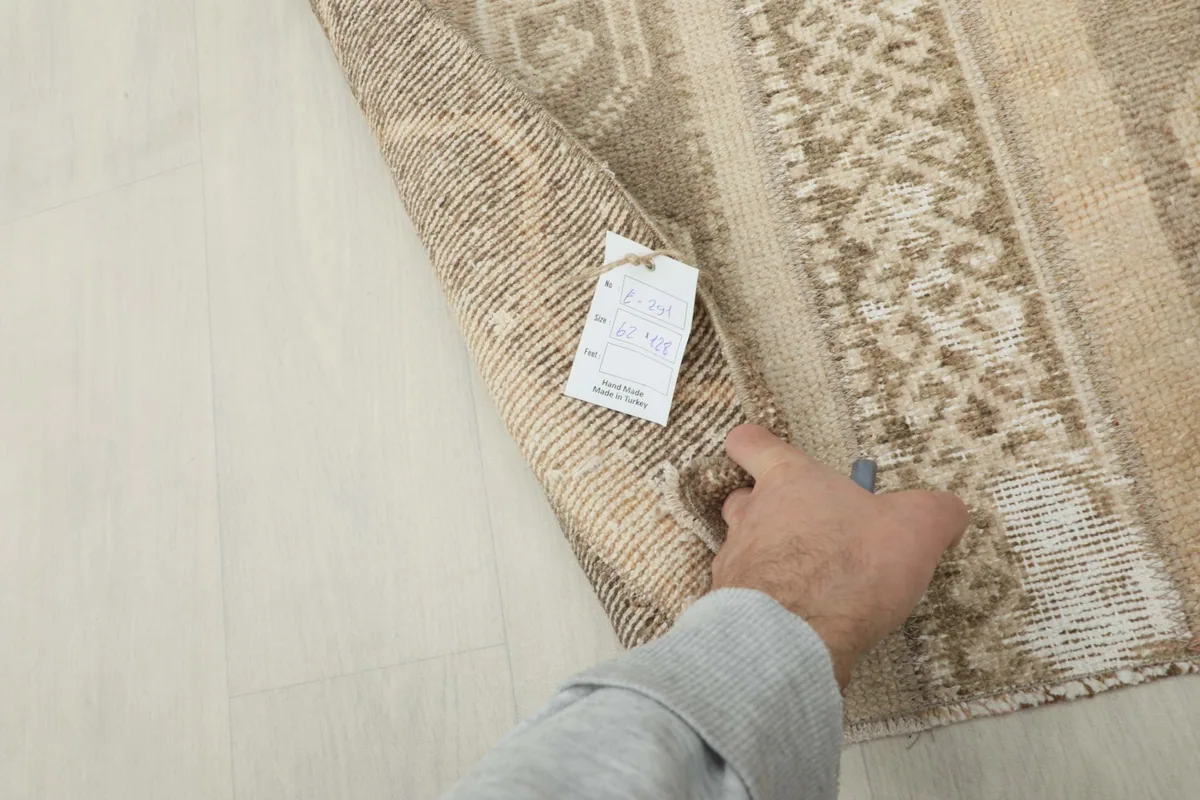 Hand holding the rug, showing the thickness and the product tag
