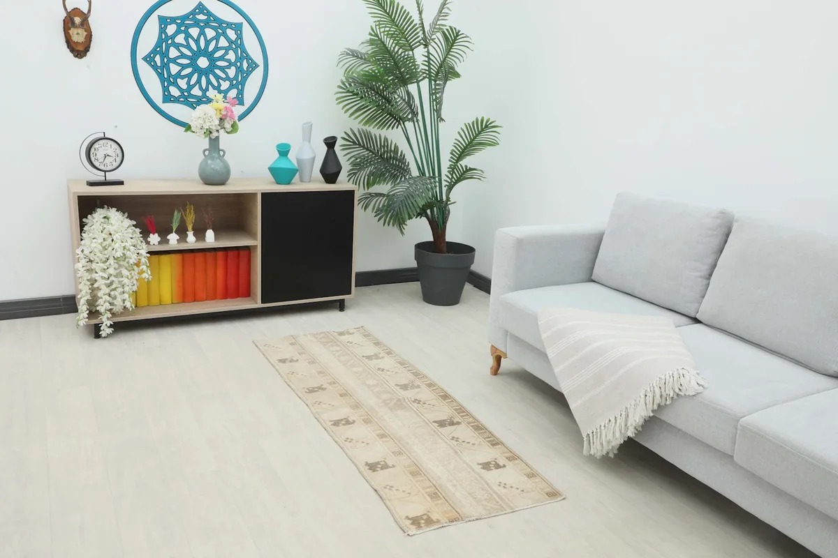 The beige runner rug displayed in a modern room setting, showing its scale next to a sofa and console.
