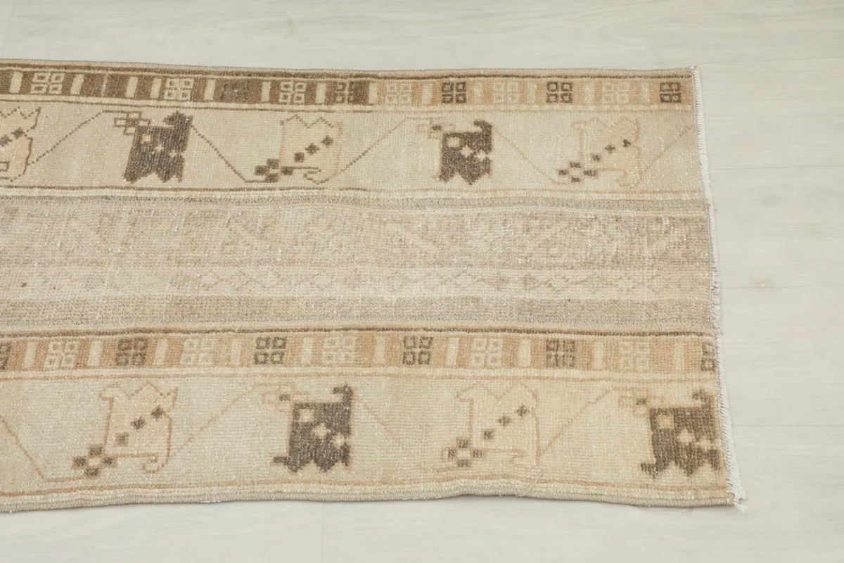 Close-up detail of the rug's beige field and brown tribal motifs along one side.