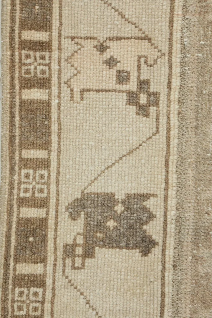 Close-up of the intricate brown geometric patterns and the woven structure of the wool pile.