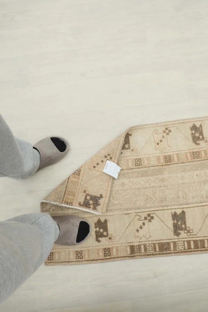 Overhead view of the rug on the floor with feet for scale, emphasizing its runner dimension.