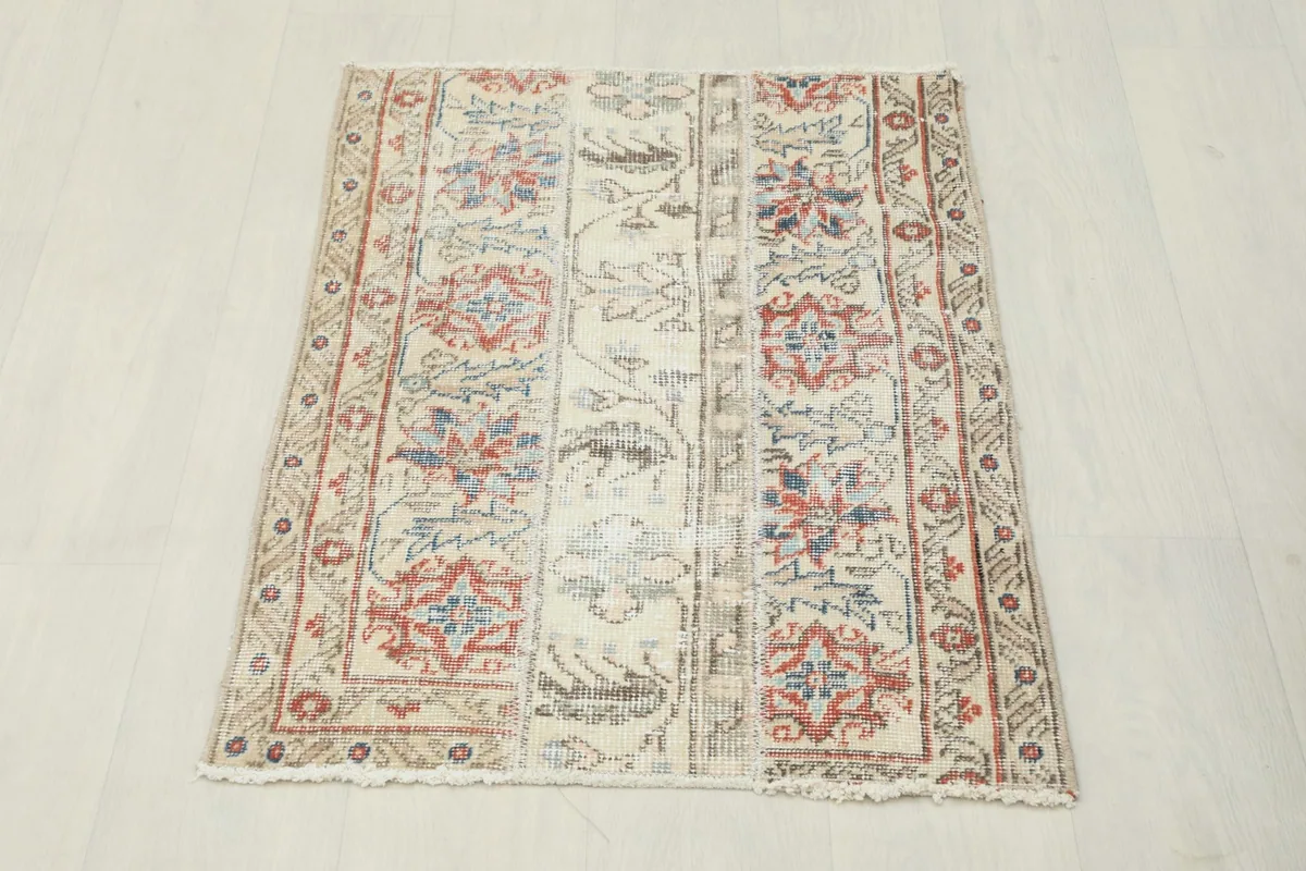 Overhead view of the beige vintage Anatolian rug with red and blue tribal floral motifs