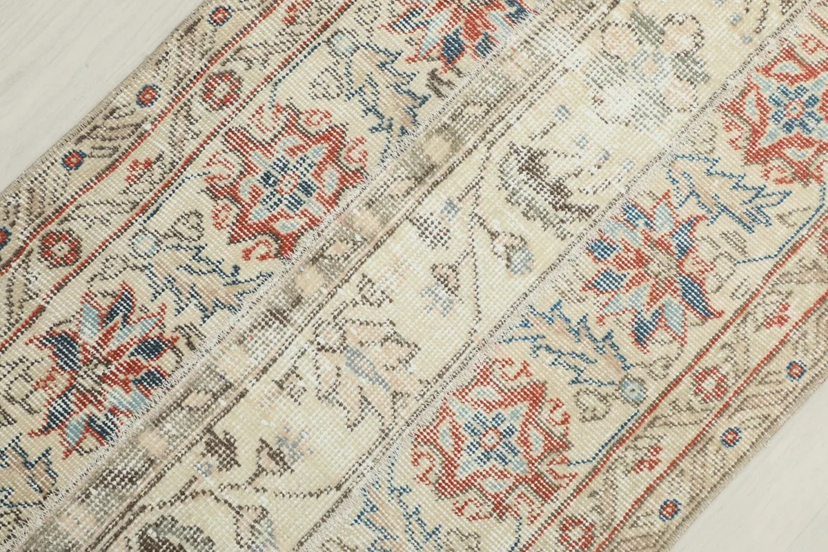 Angled close-up showing the texture and faded colors of the hand-knotted wool pile