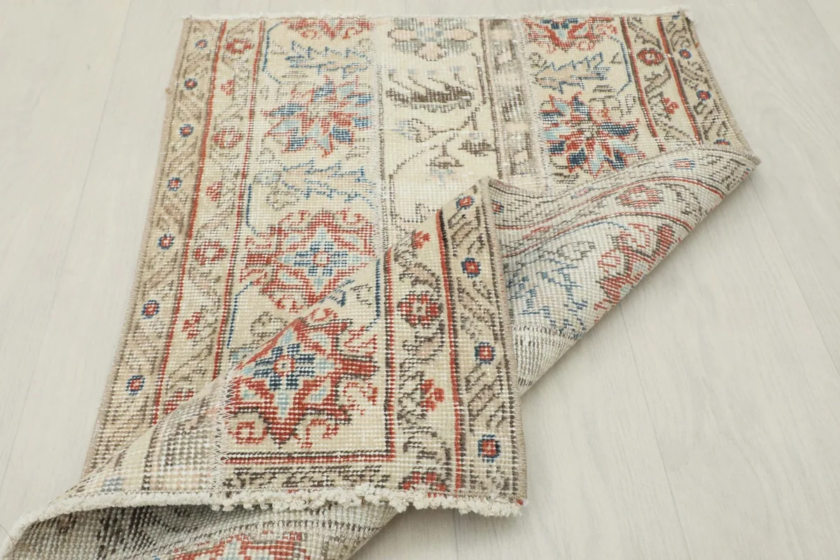 Rug partially folded, showcasing the hand-knotted construction and vintage patina