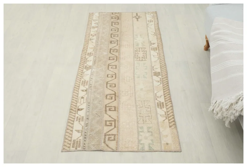 Full overhead view of the beige and tan geometric vintage runner rug on a white floor.