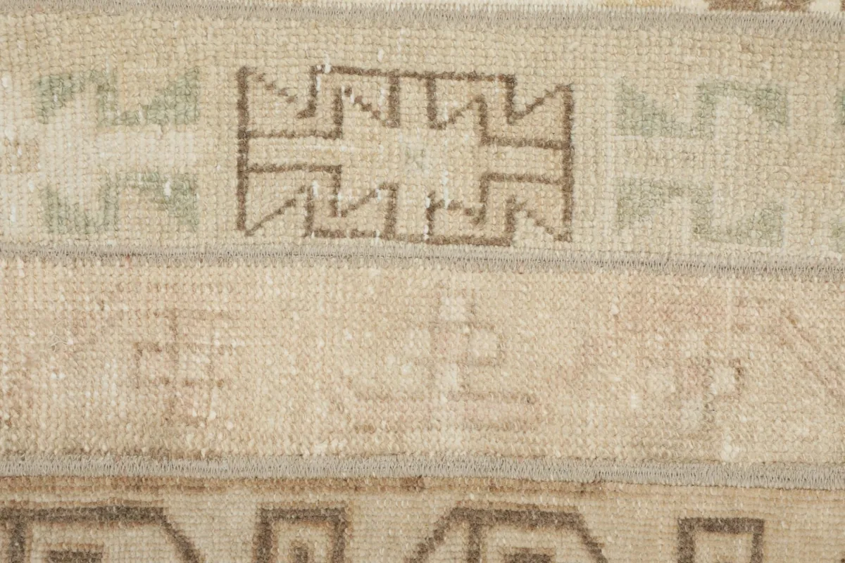 Macro detail of specific geometric patterns and the low wool pile of the vintage Anatolian runner.