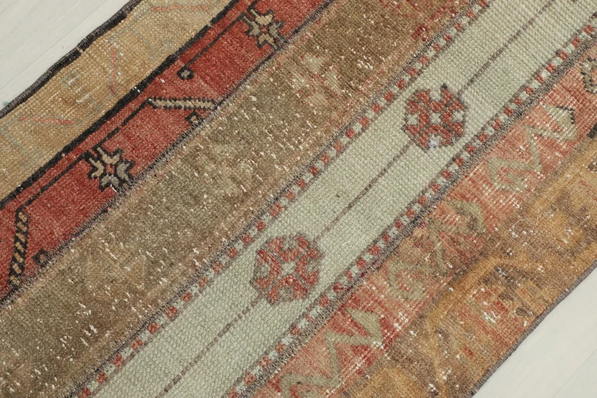Diagonal close-up of the rug's surface, focusing on the striped design and wear on the wool pile.