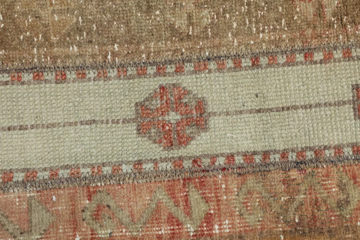 Extreme close-up of a central geometric motif within a beige stripe, showing the individual knots.