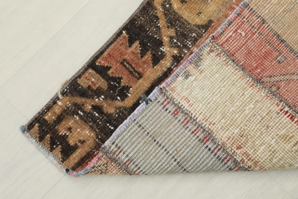 View of the back of the rug and a corner folded over, revealing the cotton foundation and knotting.