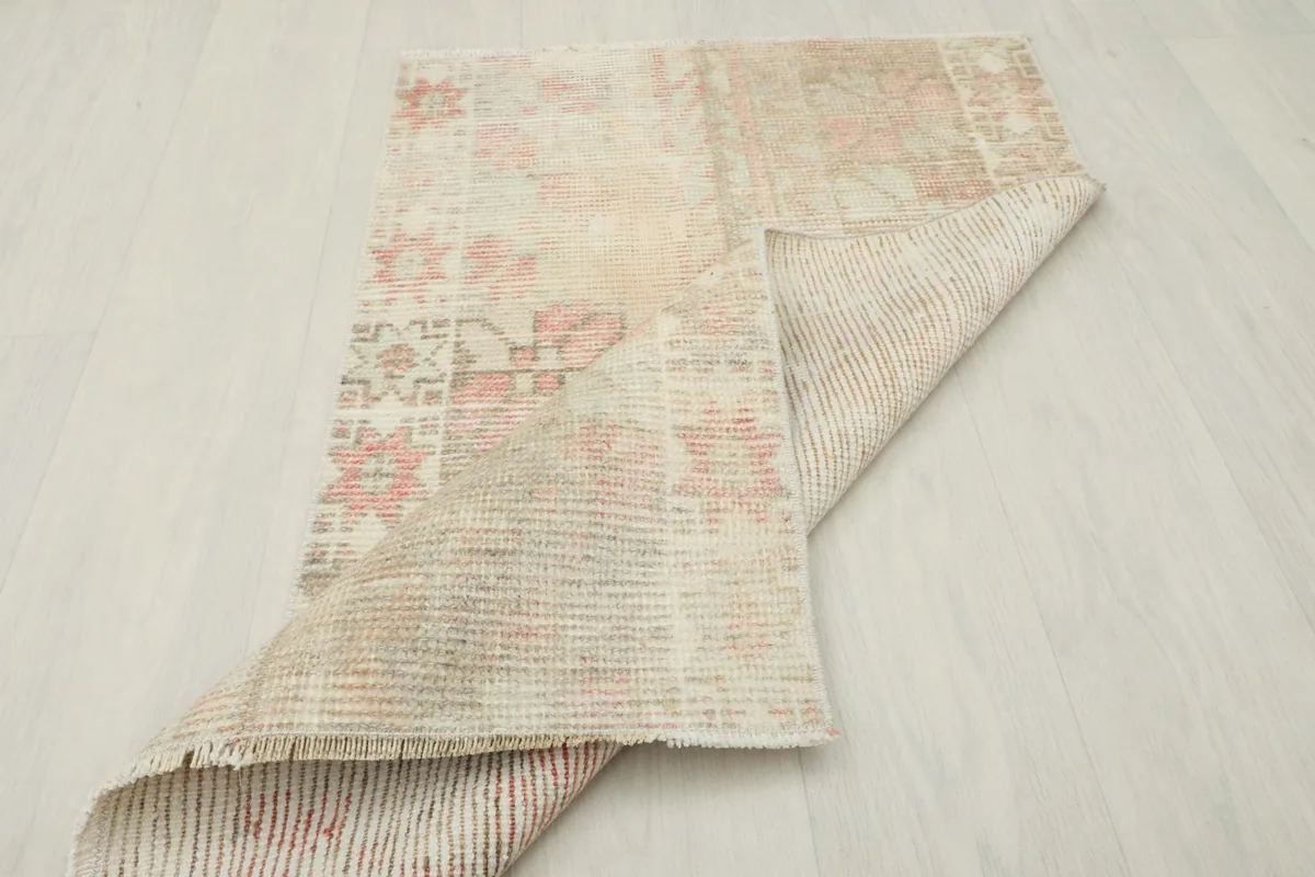 The rug partially folded to show the back, displaying the hand-knotted cotton foundation.