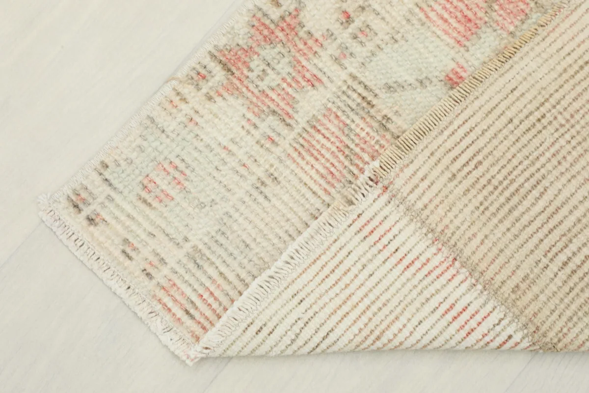 Corner of the rug folded back, revealing the cotton foundation and reverse side.