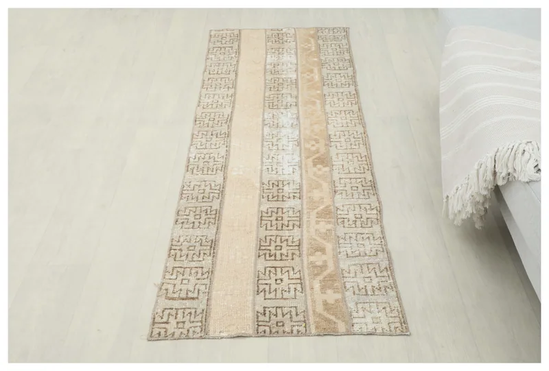 Full overhead view of a beige and brown striped geometric runner rug on a light floor.