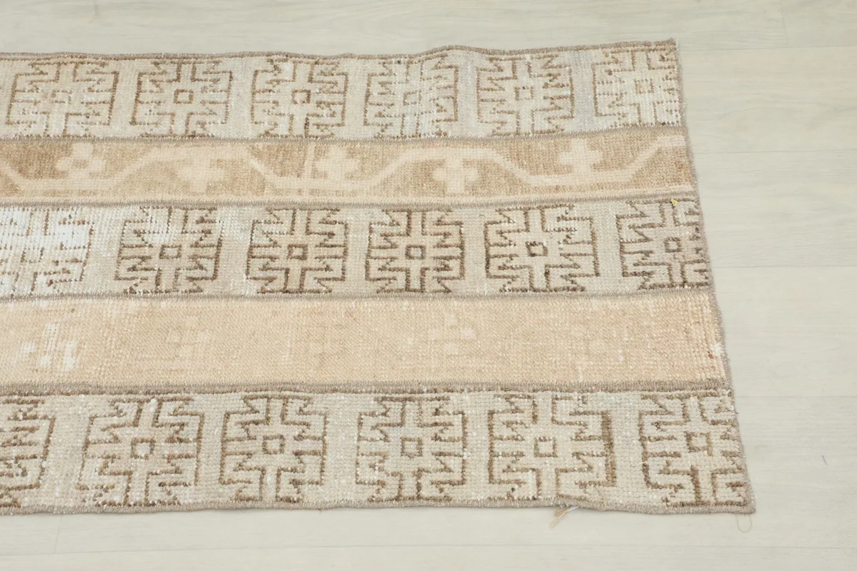 Close-up of the top end of the beige runner, highlighting the geometric patterns and subtle color variations.