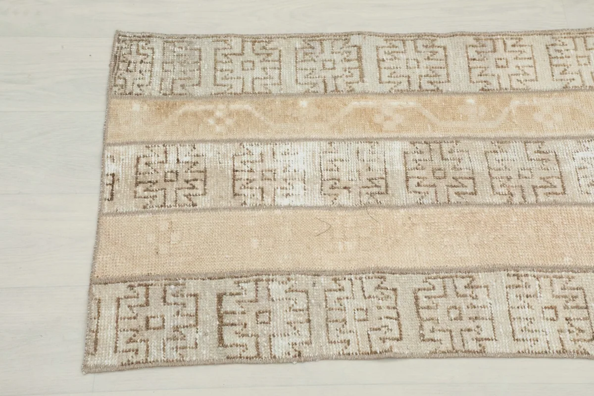 Close-up of the bottom end of the runner, showing the hand-knotted texture and beige tones.