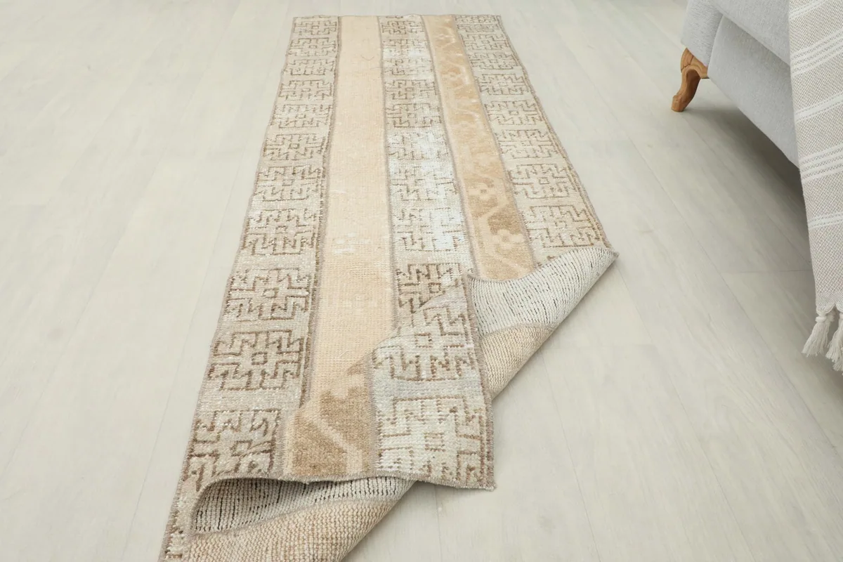Runner rug partially folded, displaying both the top surface with its patterns and the underside.