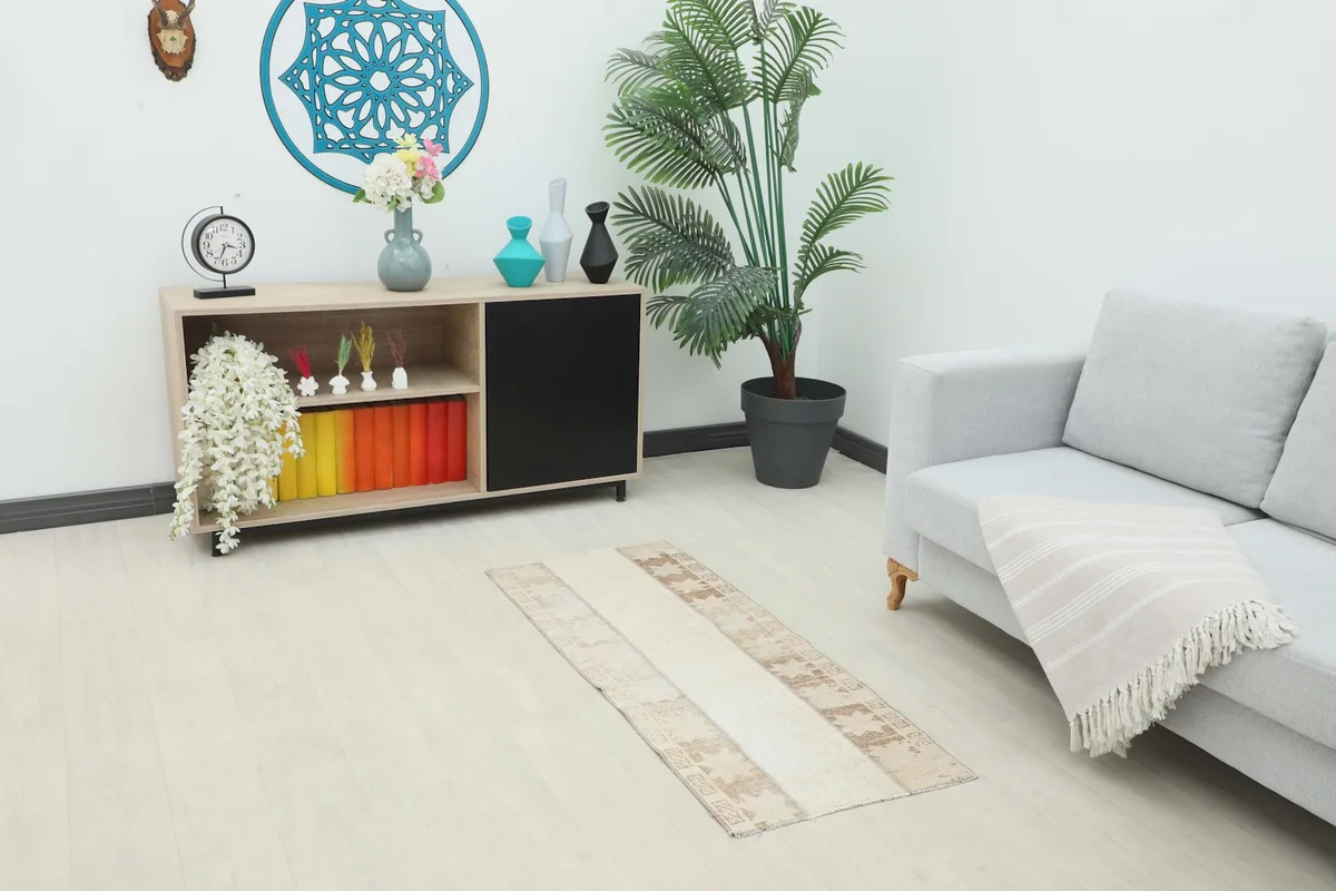 Vintage Anatolian runner rug in a modern living room setting with a light gray sofa and wooden console.