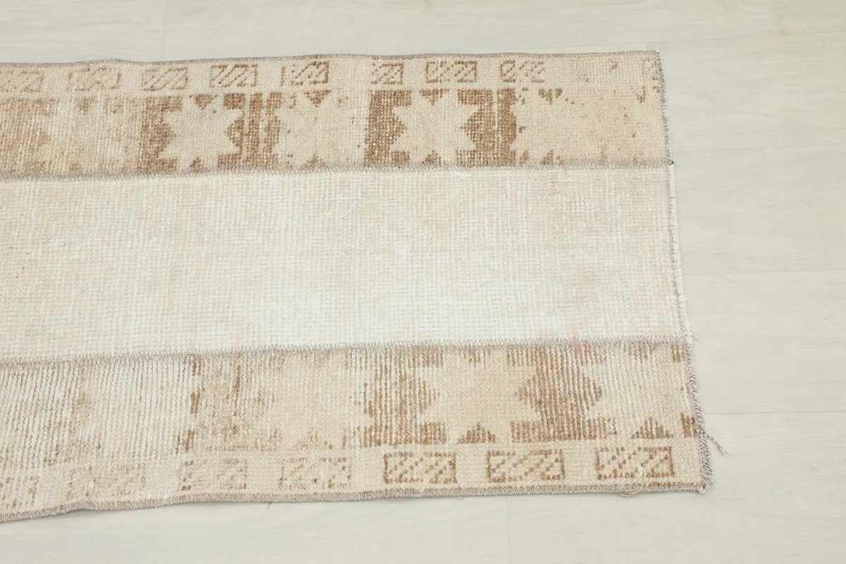 Close-up overhead view of the geometric patterns and central beige stripe of the runner rug.