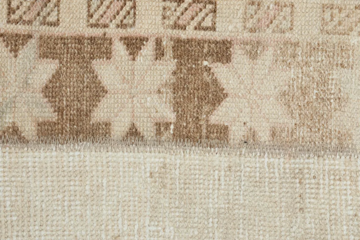 Extreme close-up of the wool pile and intricate geometric star-like patterns in tan.