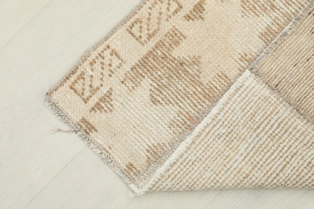 View of the back of the rug, revealing the tightly woven cotton foundation and wool knots.