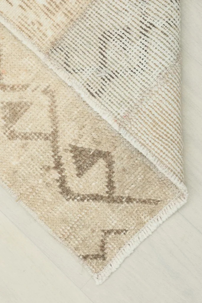 Corner of the rug folded back to reveal the cotton foundation and reverse side of the hand-knots.