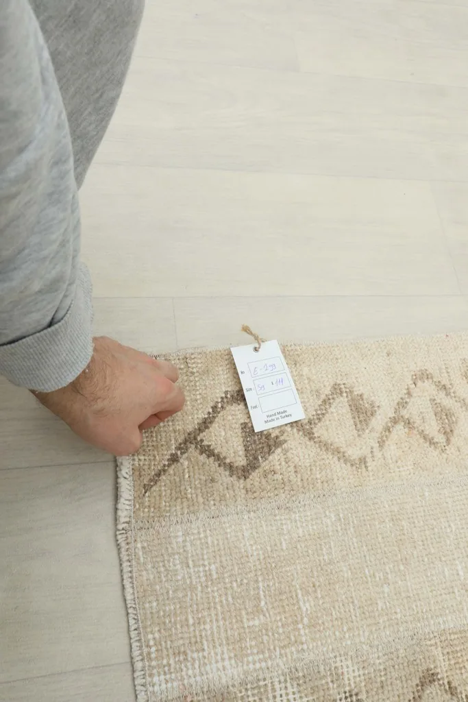 A hand holding the RugsKilim tag on the corner of the vintage Anatolian rug.